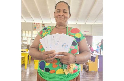 A mother holds up envelopes containing the cash grants