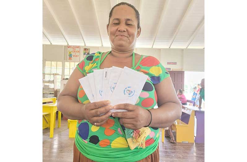 A mother holds up envelopes containing the cash grants