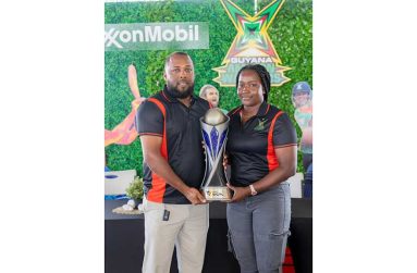 Coach Julian Moore (left) and Sheneta Grimmond display the WCPL trophy on Guyanese soil