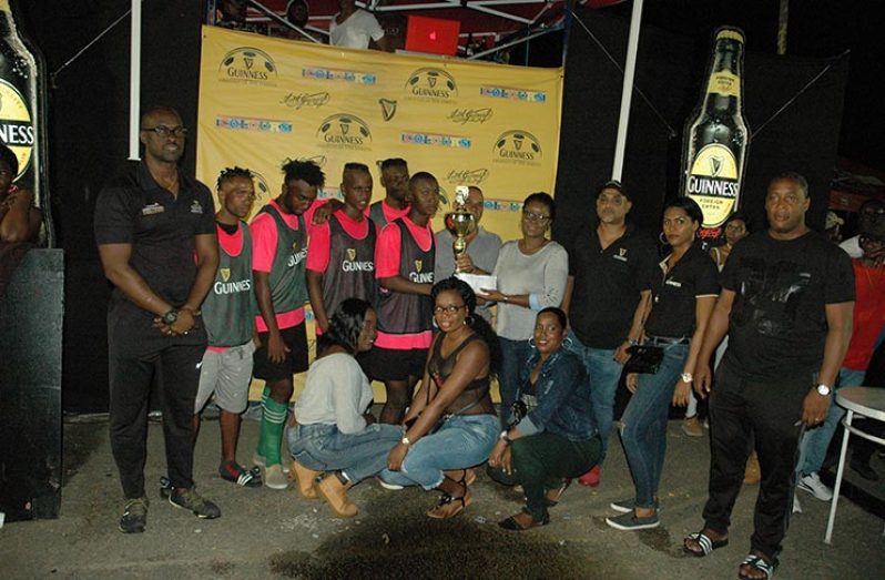 Banks DIH staffer, Fraiche Kendall, hands over the first prize and winning trophy to Trafalgar captain, Adrian Price, in the presence of Brand manager, Lee Baptiste (extreme left), Outdoor Events manager, Mortimer Stewart (right) and teammates on Sunday.