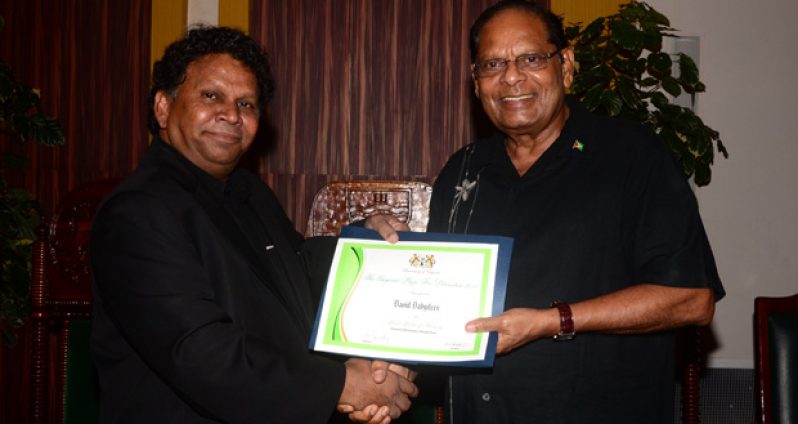 Professor David Dabydeen receiving his award for Best Book of Fiction in both categories of the Guyana Prize from Prime Minister Moses Nagamootoo on Sunday