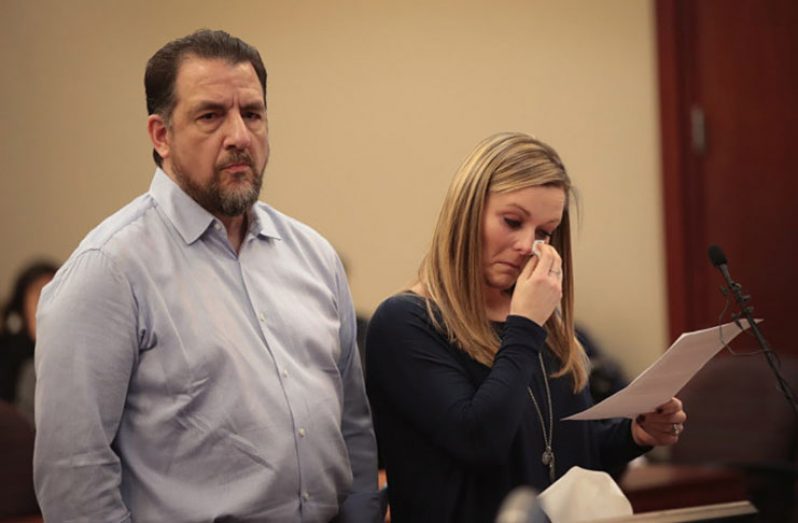 Gwen Anderson, standing with her former gymnastics coach Tom Brennan, reads a victim impact statement during Larry Nassar's sentencing hearing.