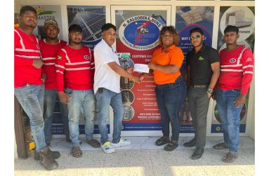 Had Ms. Akaze Thompson of RS Sports receiving sponsorship from Mr. Balgobin, CEO of N. Balgobin and Sons Contracting Service and Electrical Supplies while staff members look on