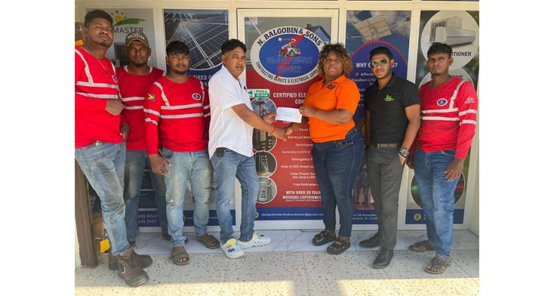 Had Ms. Akaze Thompson of RS Sports receiving sponsorship from Mr. Balgobin, CEO of N. Balgobin and Sons Contracting Service and Electrical Supplies while staff members look on