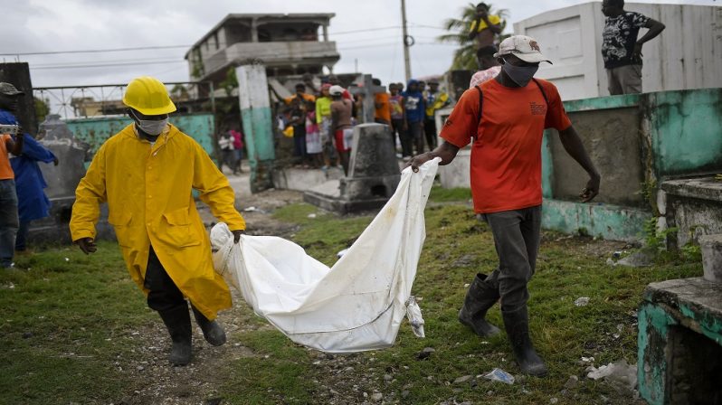 Men carry the body of a boy, who was found in a collapsed building, into the cemetery in Les Cayes, Haiti, Tuesday, Aug. 17, 2021, three days after a 7.2 magnitude earthquake hit. According to an engineer working for Les Cayes Mayor, the boy's body was found Monday amid the rubble of a collapsed hostal. (AP Photo/Matias Delacroix)