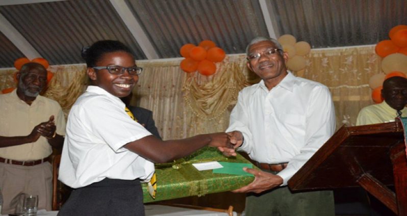 Elisa Hamilton being presented with a laptop computer by President David Granger