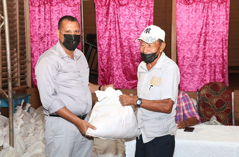 Minister of Housing and Water, Collin Croal distributes a hamper to a pensioner