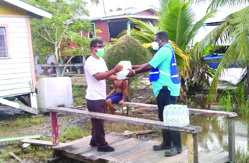 A resident of Charity collects his relief supplies from a Civil Defence Commission official