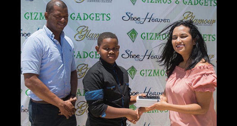 L-R: GTTA president Godfrey Munroe watches as Caribbean Table Tennis Federation (CTTF) Pre and Mini Cadet U-11 gold medallist Kaysan Ninvalle collects his Galaxy S7 from Gizmos and Gadgets manager Sophia Dolphin.