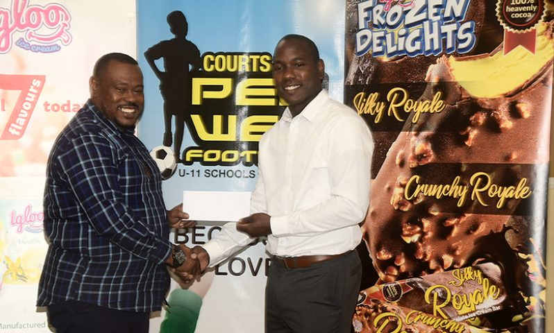 Dellon Lynch, Marketing Manager of Sterling Products Limited hands over sponsorship for the Courts Pee Wee football tournament to Petra co-director Troy Mendonca (Adrian Narine photo)