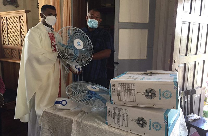 RHTYSC Hilbert Foster hands over donation of electric overhead fans to Father Ramesh Vanan of St Francis.