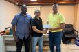 Kashif Muhammad receives contribution from QGoC Manager, Mohamed Hussein, in the presence of Aubrey Major