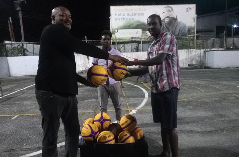 Nigel Hinds (left) hands basketballs to Bulls' Shane Lewis.