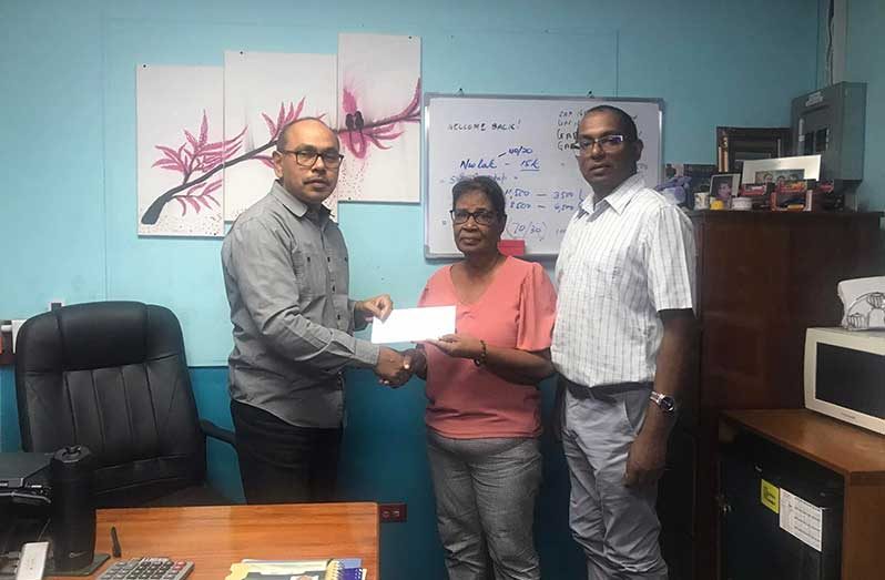 Mr. Chandradat Chintamani hands over the sponsorship cheque to Angela Haniff while BCB President Dr. Cecil Beharry looks on