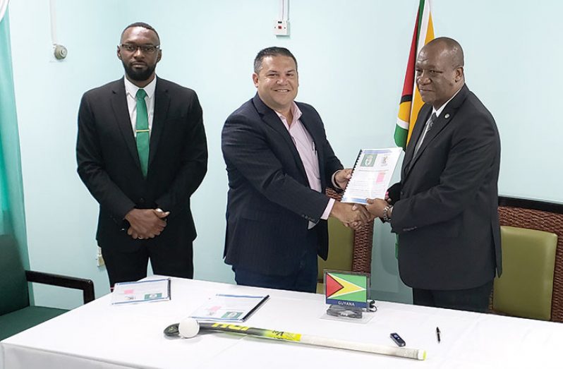 Minister of State Joseph Harmon and president of GHB, Philip Fernandes, exchange MoU while Director of Sport Christopher Jones looks on. (Rabindra Rooplall photo)