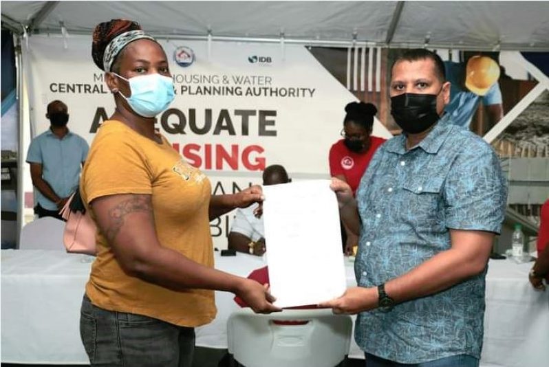 Housing and Water Minister, ColLin Croal and a resident displayed a signed contract