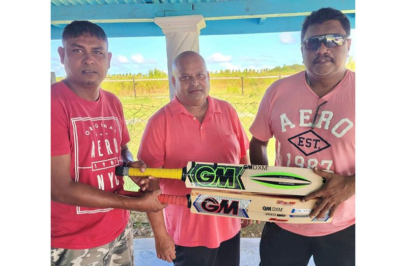 Left is owner of R. Sedatt and Son Lumber and Block Making Business, Raywan Sedatt, handing over the two bats to Mukesh Appiah (centre) and Anil Beharry