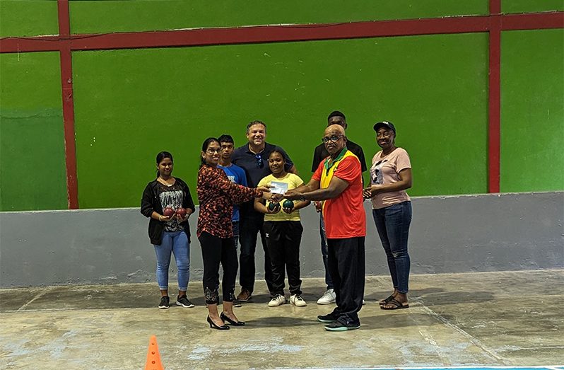 Secretary-General of the Guyana Olympic Association, Mrs. Vidushi Persaud-McKinnon (left) hands over sponsorship cheque to Mr. Wilton Spencer of Special Olympics Guyana in the presence of members of the Team and Vice-President, Philip Fernandes.