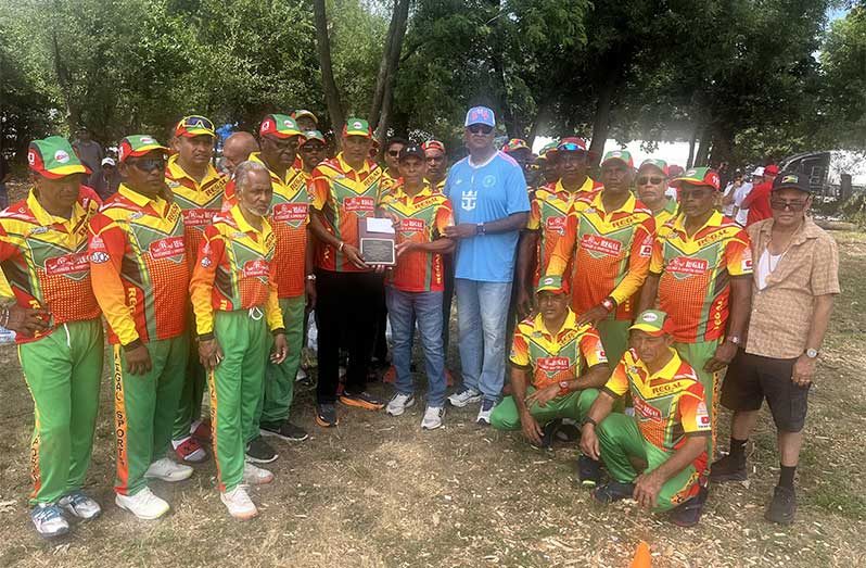 Mahendra “Anil” Hardyal, Managing Director of Regal Stationery & Computer Centre and owner of Regal softball teams, hands over the plaque and cash to Throy Kippins in the presence of Ravi Etwaroo and members of the Regal Legends team.