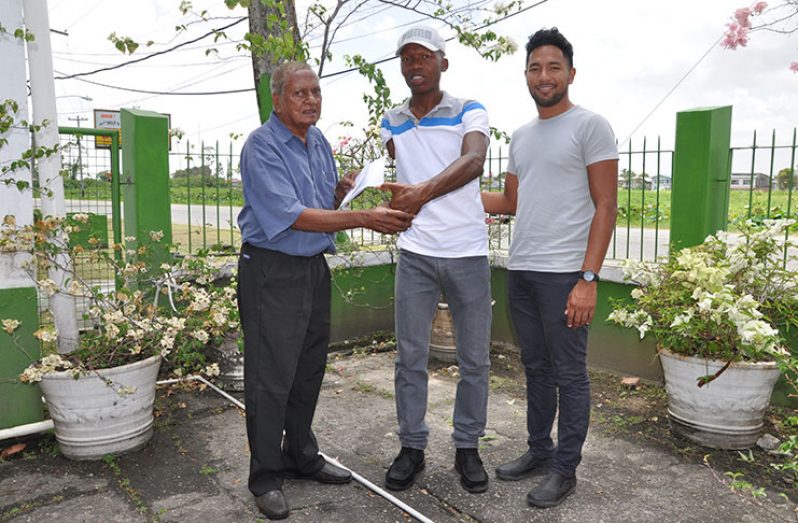 Hassan Mohamed (left) hands over the donations to Walter Grant-Stuart in the presence of national cyclist Geron Williams in the compound of the National Sports Commission (NSC).