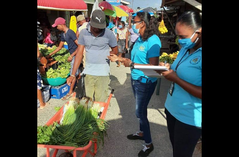 Environmental Health Workers reaching out to vendors at Suddie Market