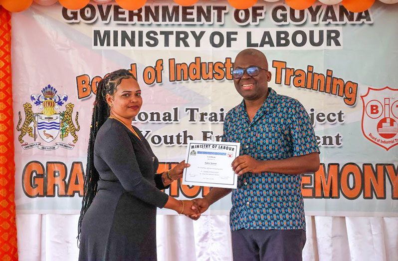 Chief Executive Officer of the Board of Industrial Training (BIT), Richard Maughn, hands over the HDEO certificate to one of the 10 women who successfully completed the programme