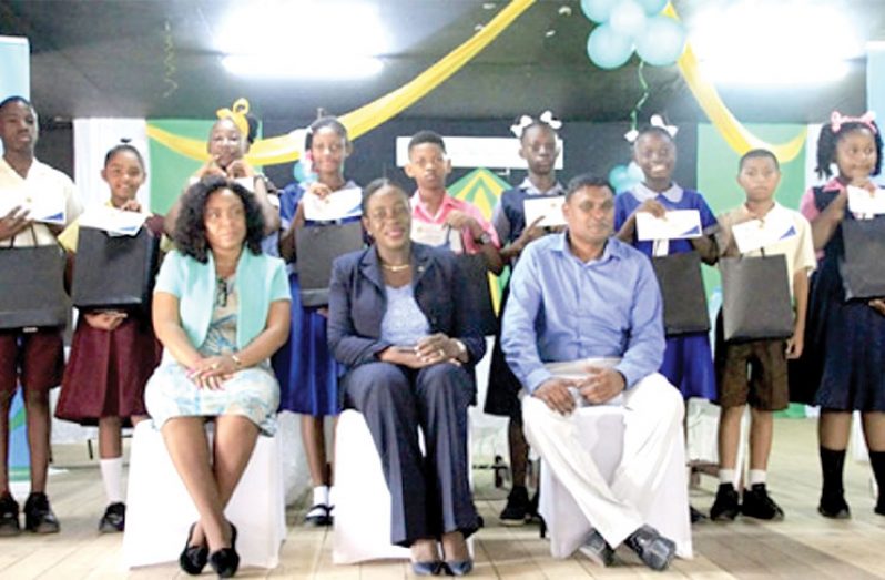 Minister Nicolette Henry; Regional Education Officer, Rabindra Singh and District Officer, Primary Shevon Brewster, with the top 10 students