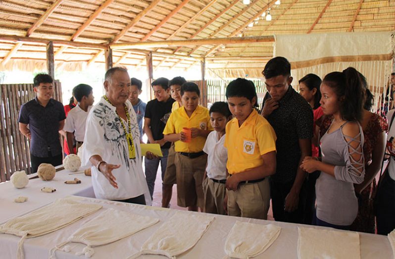 Representative of the Ministry of Indigenous Peoples’ Affairs (MoIPA), Ovid Williams, shows a group of Indigenous Youth some of the craft items that are part of their culture [Vishani Ragobeer photos]