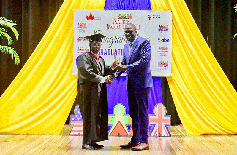 Commissioner of Police, Clifton Anthony Hicken, receives his MBA certificate from a representative of the University of Bedfordshire through Nations University Incorporated.