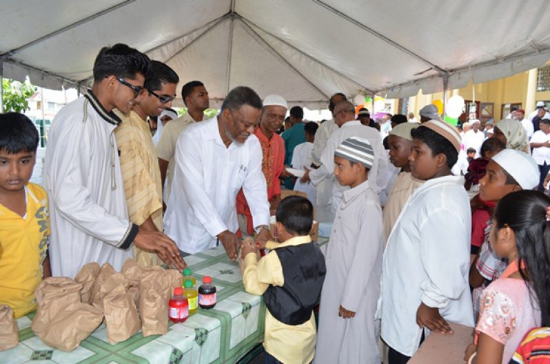 Prime Minister Samuel Hinds, along with members of the Peter’s Hall Masjid, distributing food and drinks to children at the celebration of Eid-ul-Fitr, yesterday
