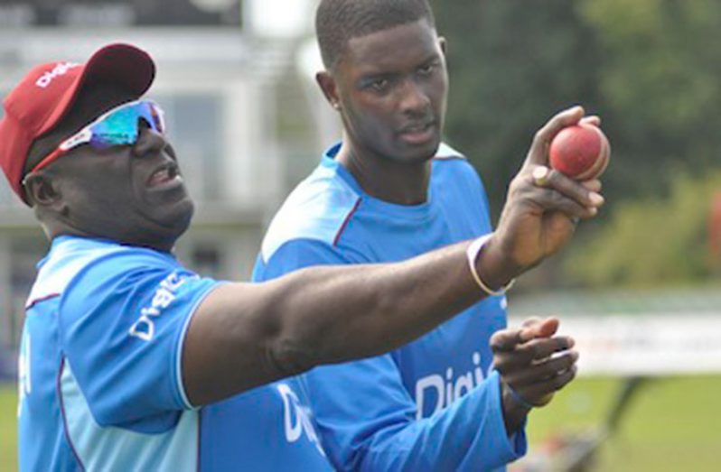 Assistant coach Roddy Estwick shows Jason Holder a bowling technique during a training session. (CWI photo)