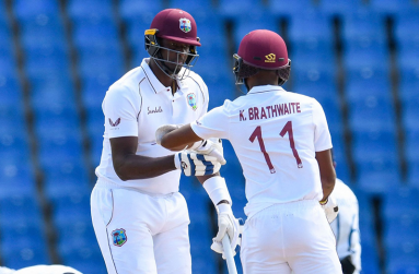 West Indies all-rounder Jason Holder, left, congratulates captain Kraigg Brathwaite for reaching his half-century during day one of the second Test against Sri Lanka at Vivian Richards Cricket Stadium in North Sound, Antigua. (Photo by RANDY BROOKS/AFP via Getty Images)