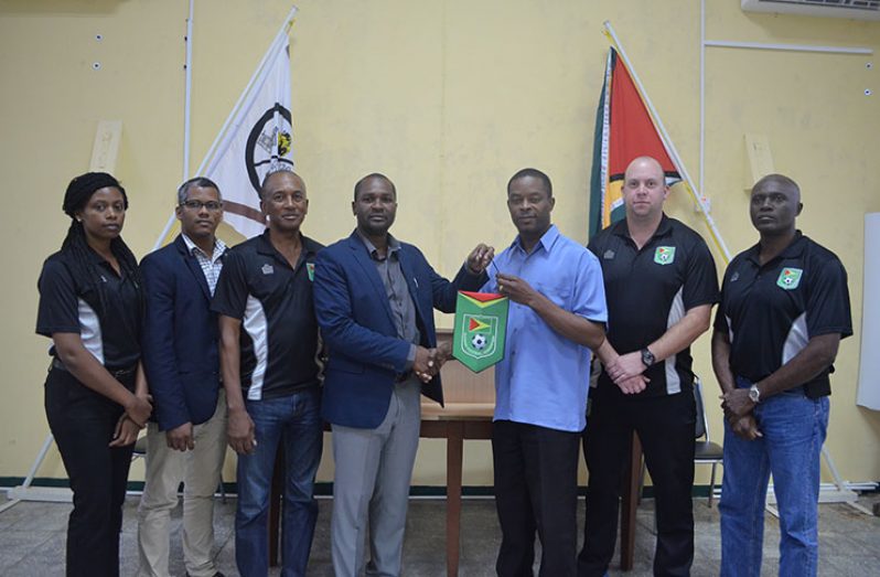 GFF president Wayne Forde presents the GFF pennant to Mayor of Linden,Carwyn Holland,in the presence of other GFF and MSC officials