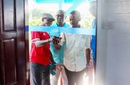 Minister within the Office of the Prime Minister with responsibility for Public Affairs, Kwame McCoy, oversees the cutting of the ribbon by Albert Hunte and his son