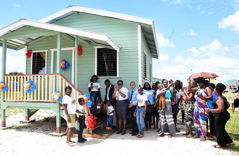 Former informal settlers of Lombard and Broad Streets rejoice as CEO of CH&PA, Lelon Saul, and a toddler, cut the ceremonial ribbon to commemorate the handing of over of the 20 housing units. Joining the celebrations were Minister within the Ministry of Housing, Annette Ferguson, and CEO of FFTP Guyana, Kent Vincent (Adrian Narine photo)