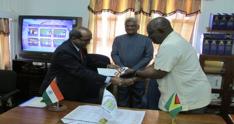 Indian High Commissioner, Mr. V. Mahalingam, hands over the cheque to Mr. Keith Lowenfield. Standing at the back is GECOM Chairman, Dr. Steve Surujbally