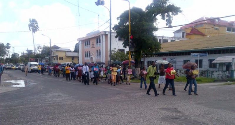The group of marchers against the five per cent increase make their way along Brickdam as they cross Camp Street.