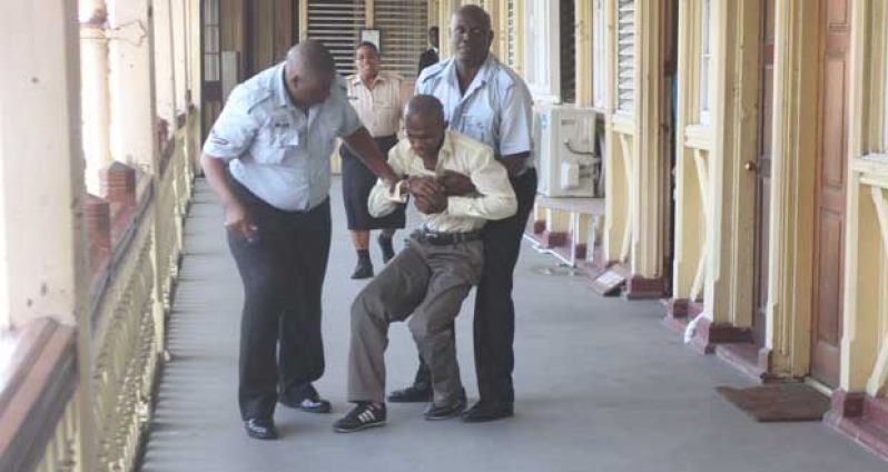 Police succeed in restraining a convicted Kevin Verwayne (in handcuffs) leaping to his death over the Court’s railing after learning he’d have to spend the rest of his life in jail