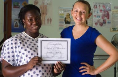 Nurse Aide, Patricia Stewart and Peace Corps Response Volunteer, Kera Murphy, celebrating Ms. Stewart receiving a certificate after demonstrating resident care skills in positioning and self-care following training