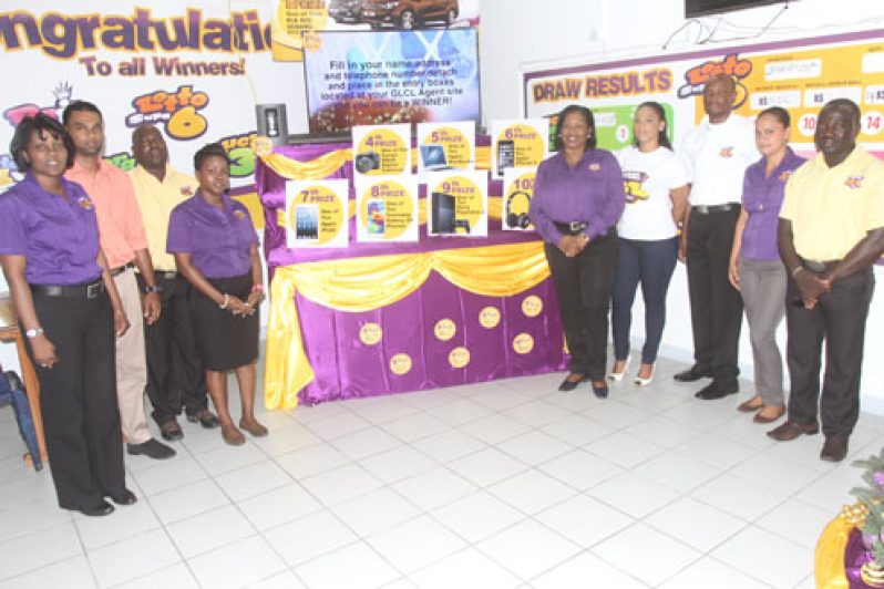 GLC staffers stand beside the display of prizes that can be won in the ‘Best of the Best’ promotion, yesterday (Sonnel Nelson photos)