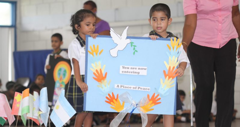 Two students of Marian Academy Nursery, assisted by a teacher, portray their message of peace to members of the gathering.