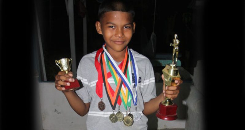 Roberto displays his medals and some of his trophies won for athletic championship.