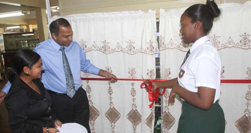 From left are Administrator of the Guyana National Museum, Ms. Nadia Madho, Dr. Frank Anthony assisting student of Bishops’ High School, Ms. Rojeria McWatt in cutting the ribbon to formally unveil the new technology installed in the museum
