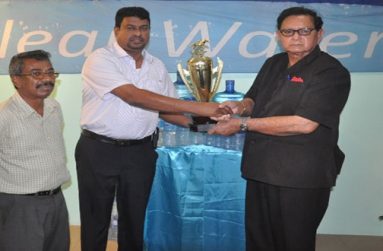 Retired Chief Justice Cecil Kennard (right) accepts the winning trophy for the J3 event from IPA CEO Lloyd Singh in the presence of IPA manager Bowhan Balkarran.