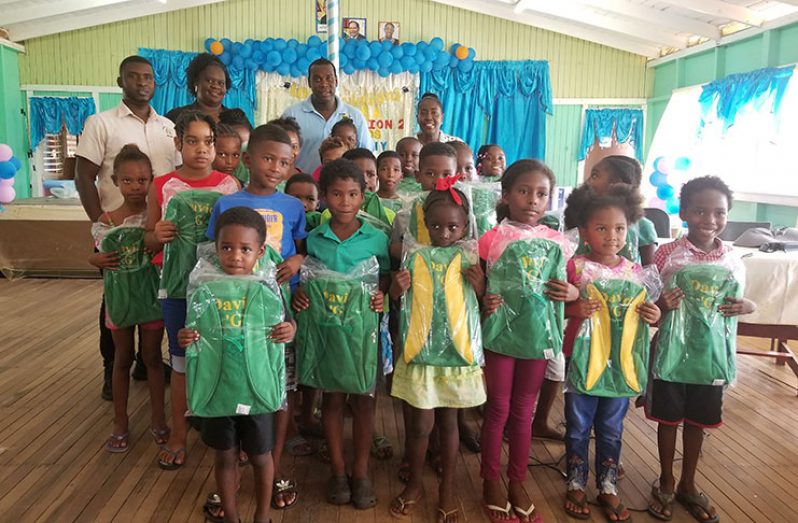 Minister Yearwood and other regionals officials standing with pupils of the Howell Wilson Primary School who were more than happy to ‘show off’ their new bags.