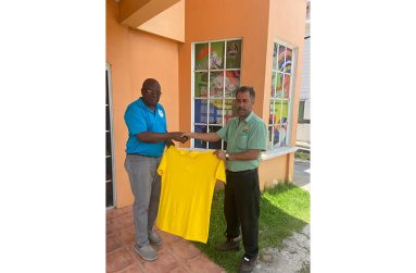 Assistant Manager Eon Vieira, right, hands over a jersey to GSCL President Ian John