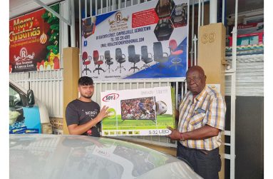 Manager of Regal Sports Store, Ian John hands over one of the televisions to a representative of Roraima Developers