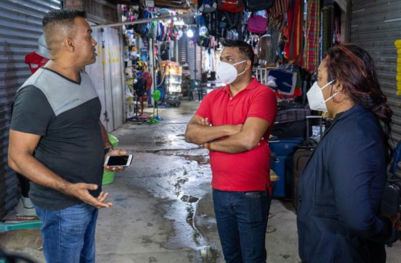 Minister within the Ministry of Public Works, Deodat Indar; Government Member of Parliament, Dr. Tandika Smith, listening to the concerns of a vendor at the Parika market
