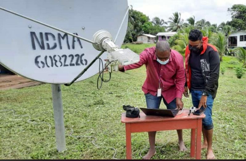 The technicians from NDMA in the community of Akawini in the Lower Pomeroon checking the Internet connectivity.