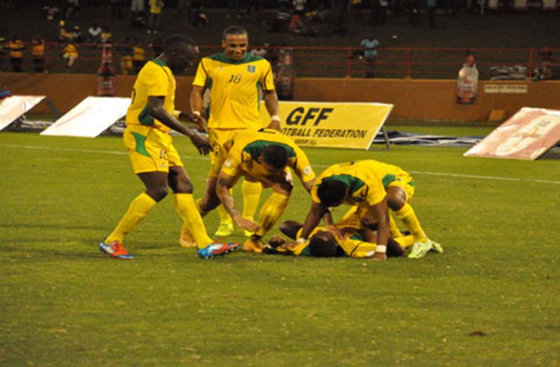 Flashback to 2015! Guyana’s Pernell Schultz (on the ground) is swarmed by Walter Moore (right), (L-R) Joshua Brown, Neil Danns and Matthew Briggs after scoring his second goal against Grenada. (Delano Williams photo)